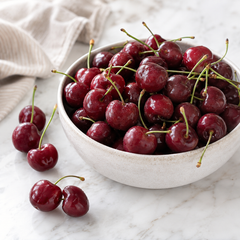 Bowl of cherries on a marble surface with a light background