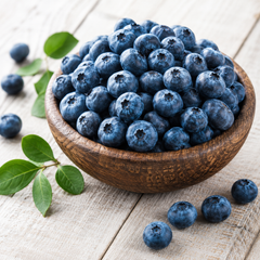 Wooden bowl filled with blueberries on a light wooden surface
