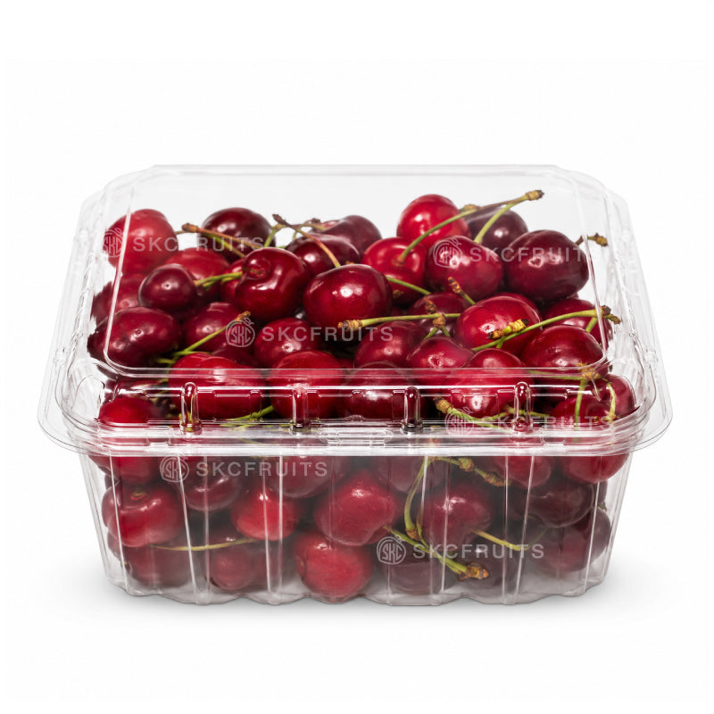 Clear plastic container filled with red cherries on a white background