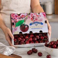 Box of Wando Valley Farms cherries held by a person with a kitchen background