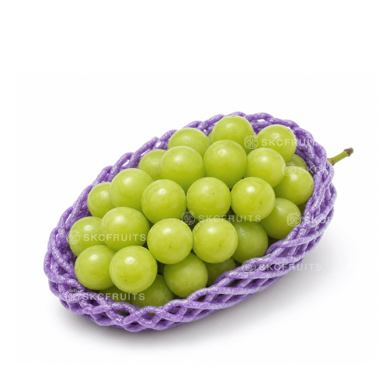 Green grapes in a purple woven basket on a white background