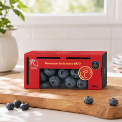 Box of Royal blueberries on a wooden cutting board with a blurred indoor background